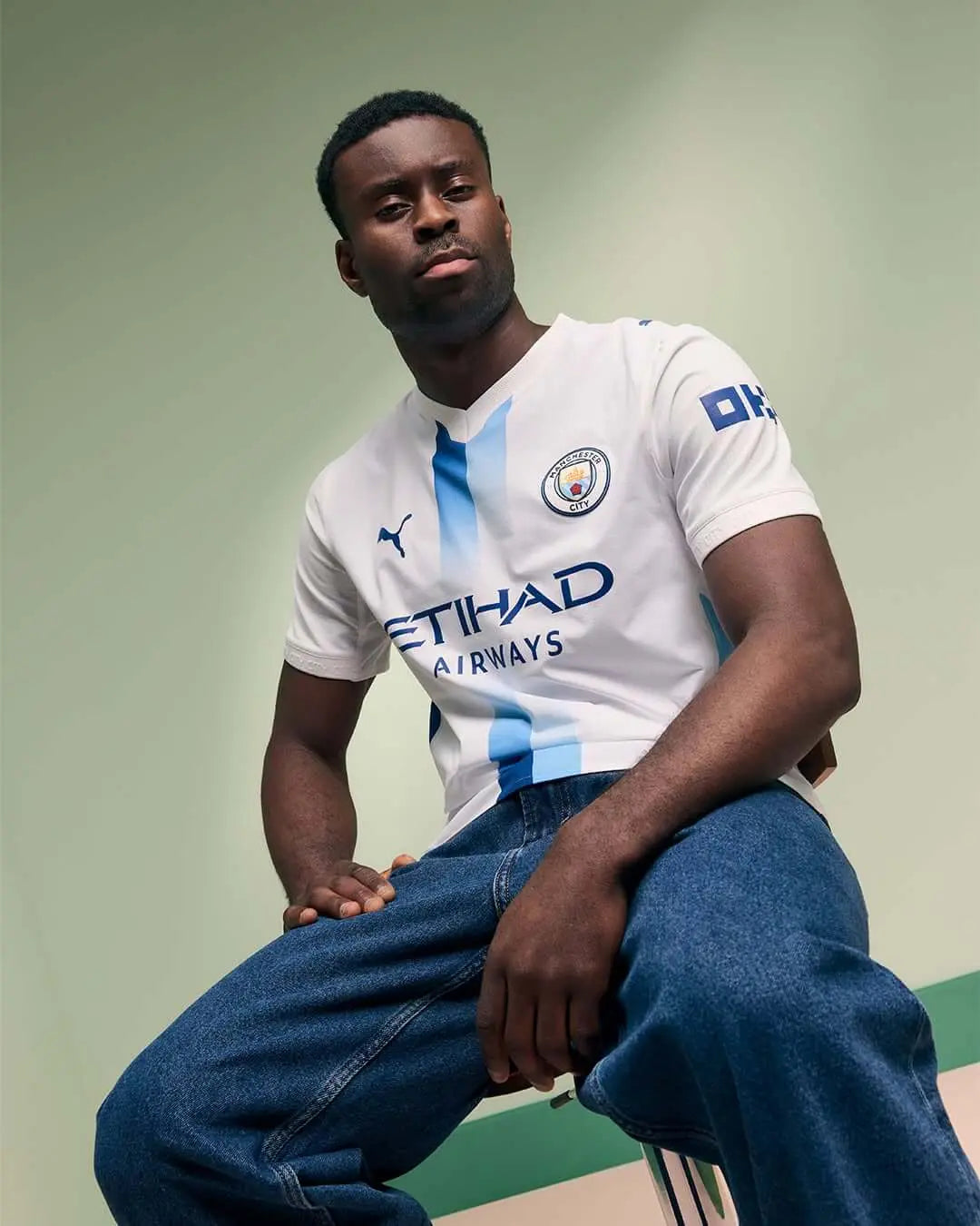 Camisa Manchester City III 2026/27 Torcedor Puma masculina branca, com faixa vertical em azul-celeste e azul-marinho criada a partir de projeto escolhido pelos torcedores.