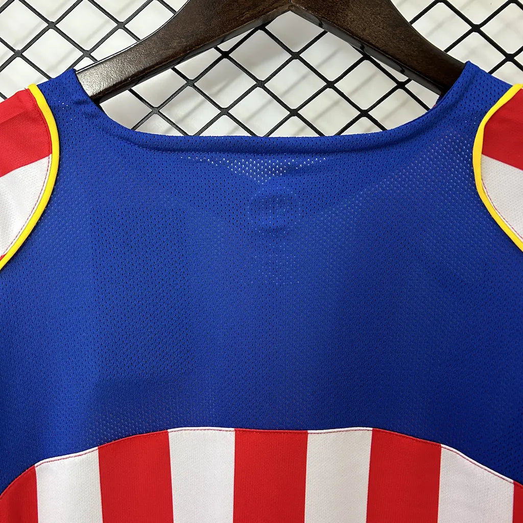 Camisa titular de manga longa do Atlético de Madrid 2004/05 vista de frente, com listras vermelhas e brancas, escudo do clube e o icônico patrocínio do filme Spider-Man 2. costas detalhes