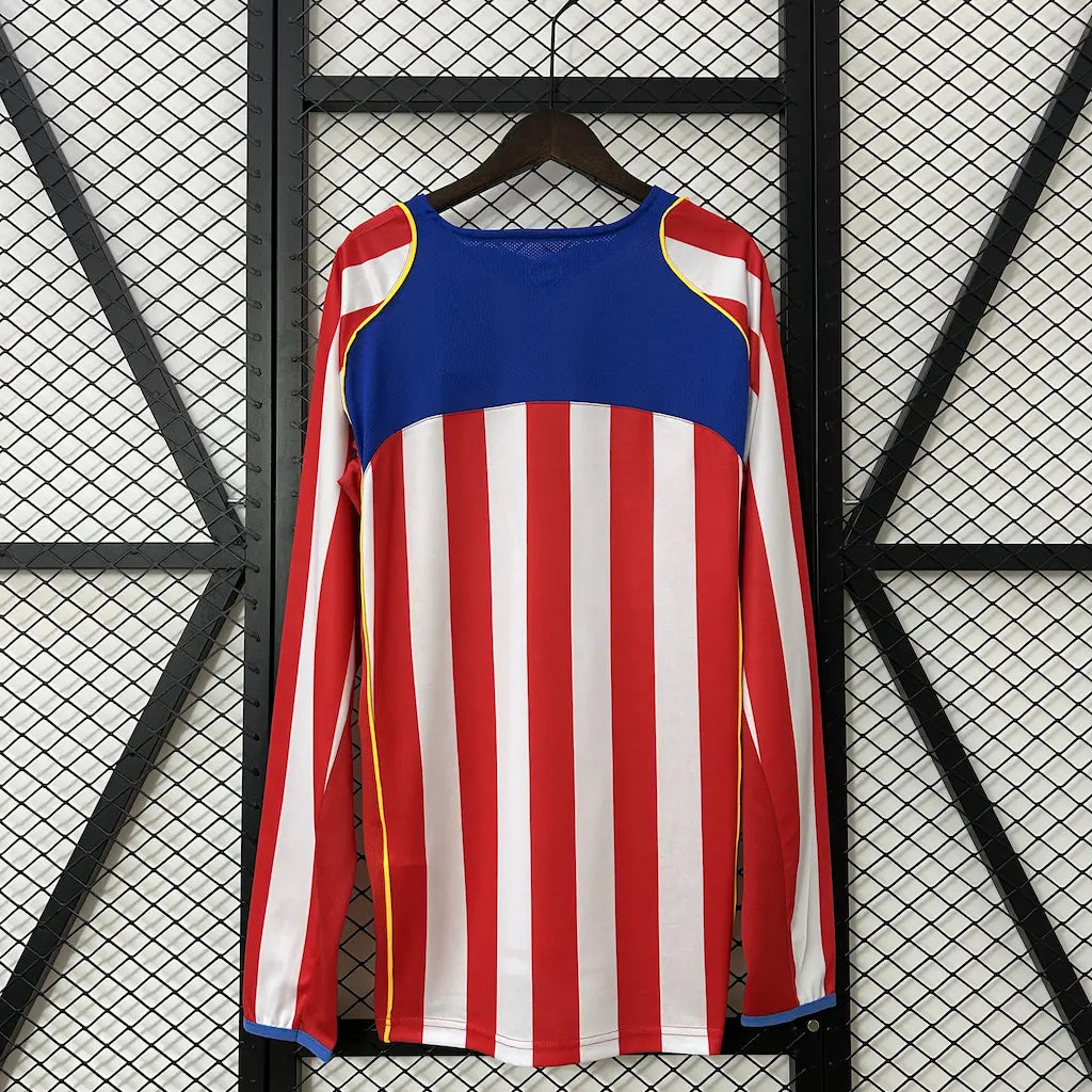 Camisa titular de manga longa do Atlético de Madrid 2004/05 vista de frente, com listras vermelhas e brancas, escudo do clube e o icônico patrocínio do filme Spider-Man 2. costas