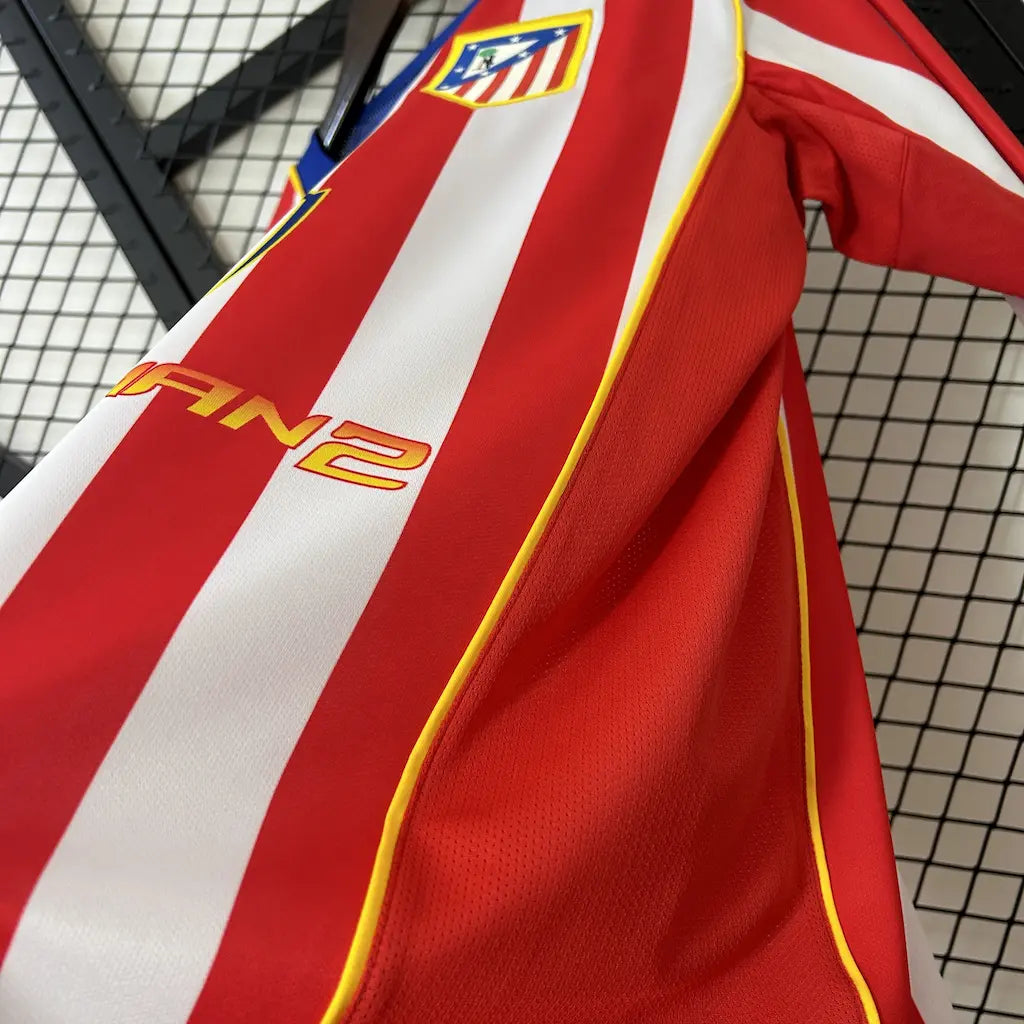 Camisa titular de manga longa do Atlético de Madrid 2004/05 vista de frente, com listras vermelhas e brancas, escudo do clube e o icônico patrocínio do filme Spider-Man 2. detalhes tecido